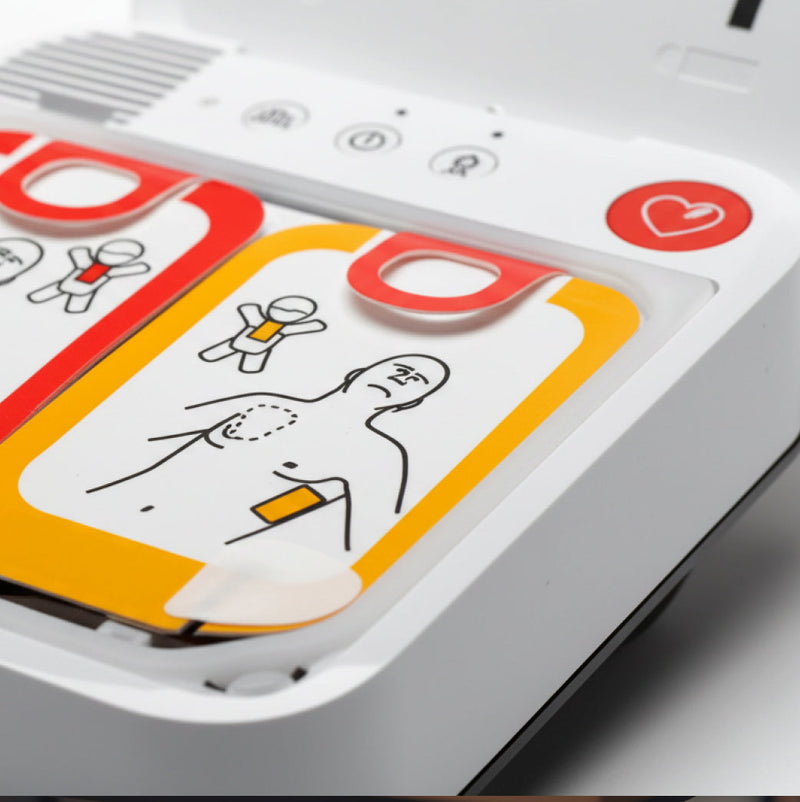 Close-up of an automated external defibrillator with illustrated instructions on pad placement for chest use.
