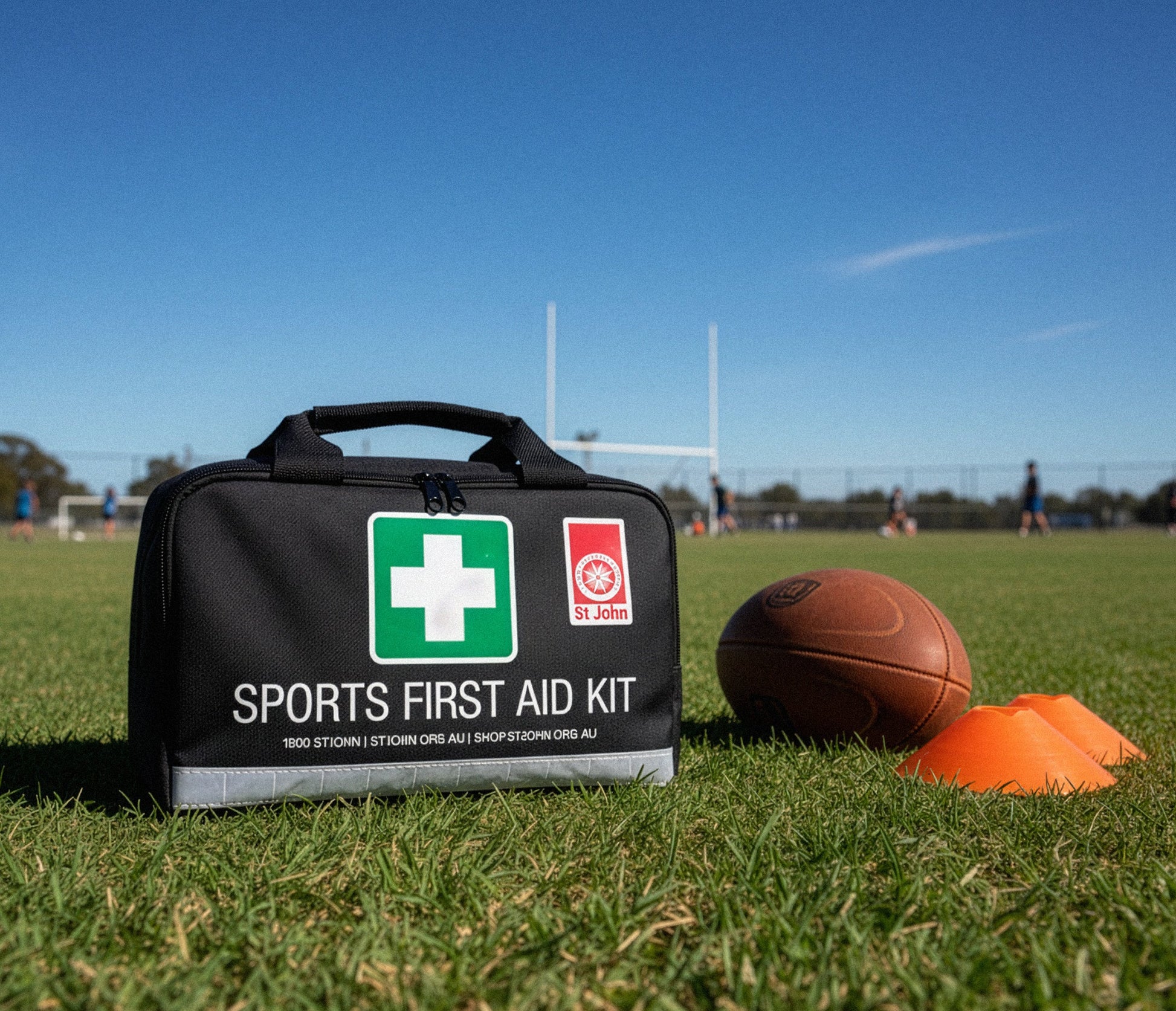 Sports First Aid Kit on grass near rugby ball and training cones for quick first aid in sports and outdoor activities