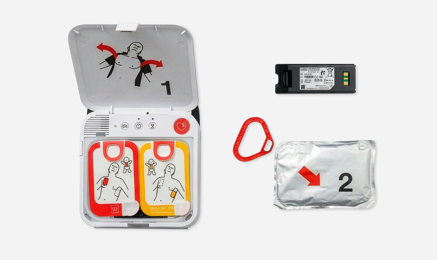 Open automated external defibrillator with labeled pads, battery, red plastic tool, and sealed accessory pack displayed on white background